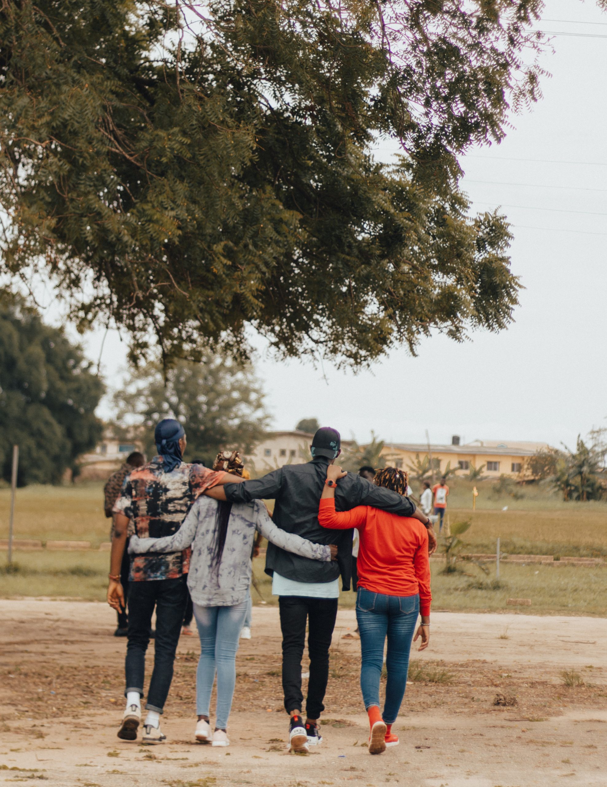 Four friends walking together with their arms around each other.