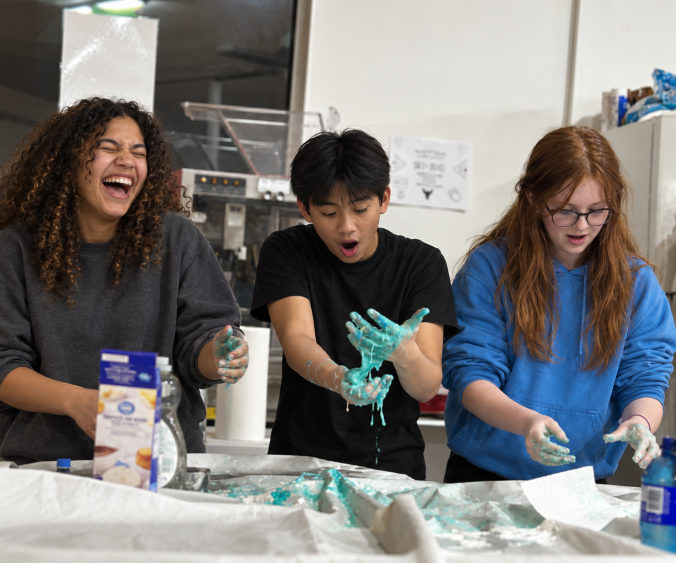 AI-generated image of three teens laughing and making turquoise slime.